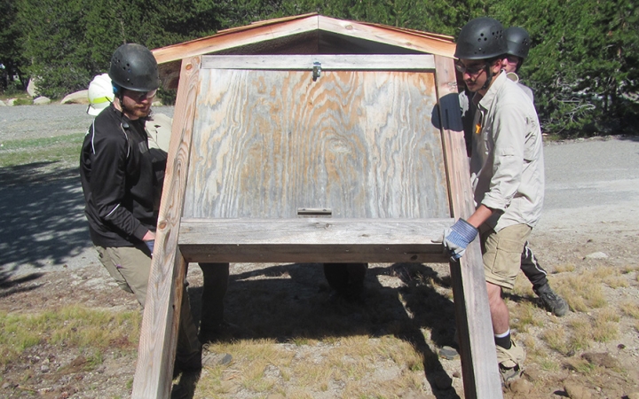 Two students raise a trail sign during a service project with outward bound. 